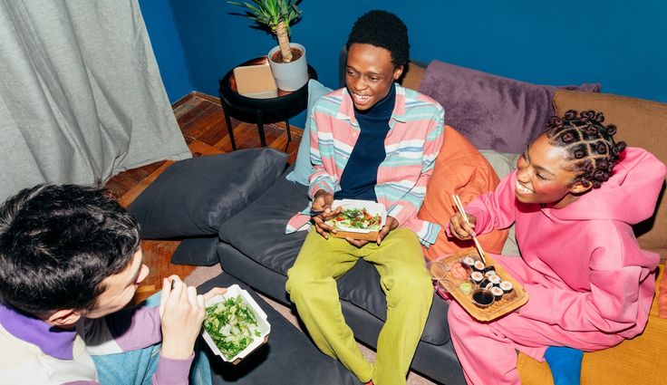 Multiracial friends eating dinner in living room and having fun